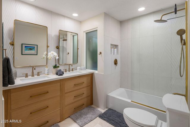 a bathroom with a double vanity sink toilet mirror and bathtub