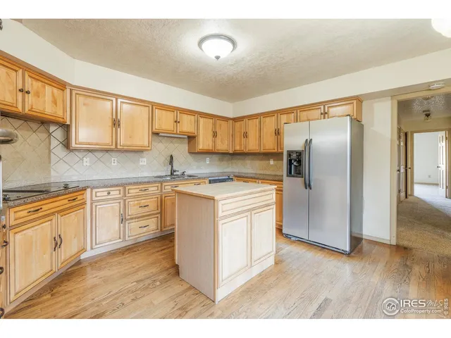 a kitchen with stainless steel appliances granite countertop a refrigerator a sink a stove and oven with wooden floors