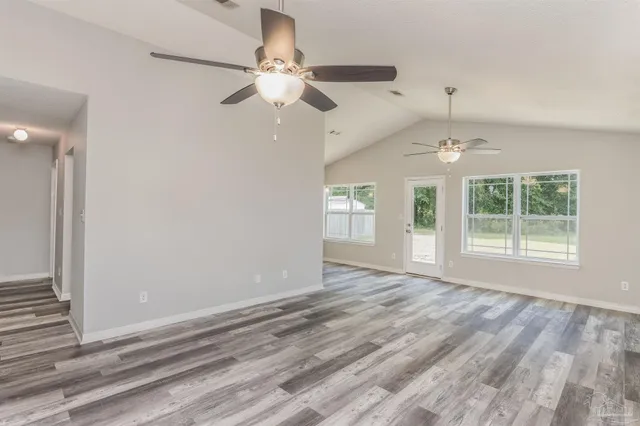 an empty room with wooden floor fan and windows