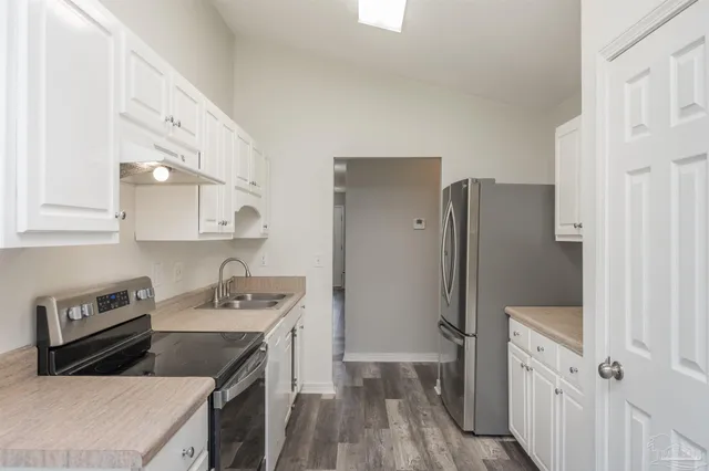 a kitchen that has a refrigerator a sink and wooden floor