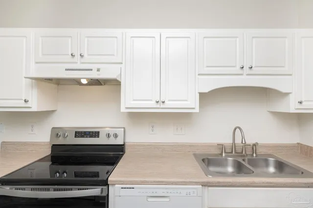 a kitchen with granite countertop white cabinets and a stove