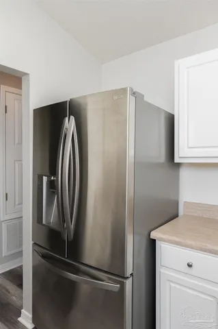 a view of a refrigerator in kitchen and white cabinets