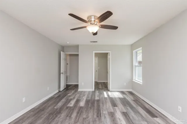a view of empty room with wooden floor and ceiling fan