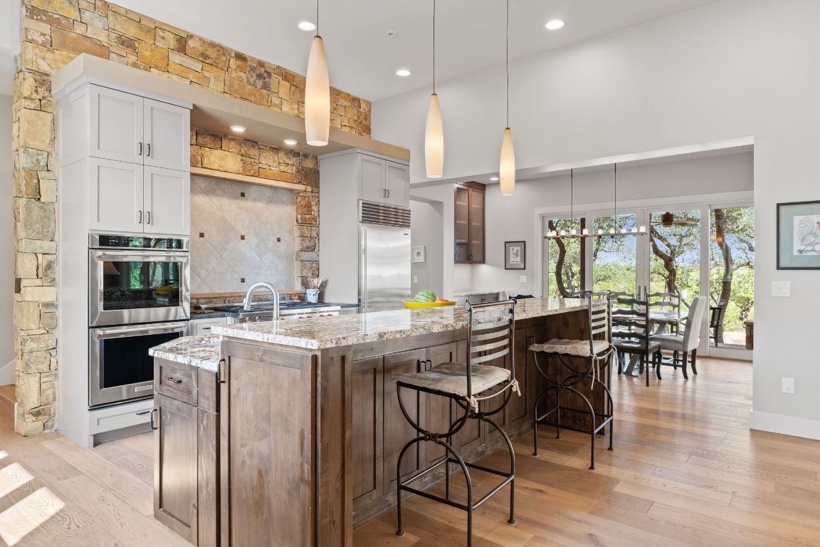 11400 Crumley Ranch Road Austin, TX 78738 - Photo 12 of 39 a kitchen with stainless steel appliances granite countertop table chairs stove and kitchen island