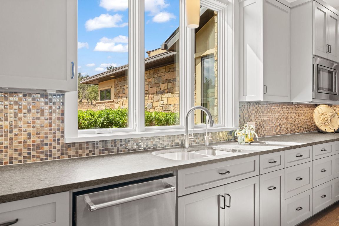 11400 Crumley Ranch Road Austin, TX 78738 - Photo 14 of 39 a kitchen with granite countertop a sink a potted plant and a large window