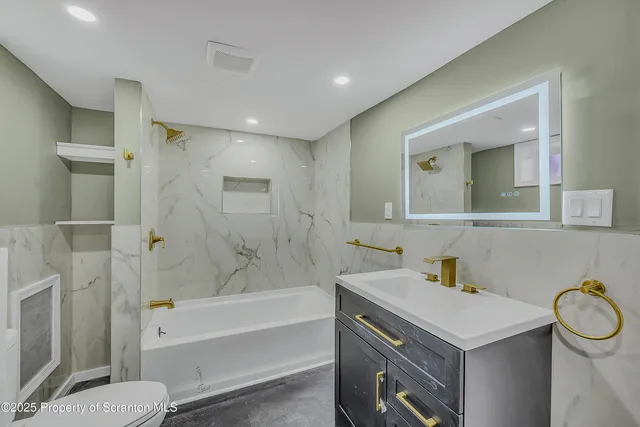 a bathroom with a sink toilet vanity and tub