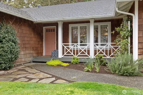 a view of a house with small yard plants and chairs