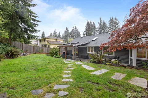 a view of a house with a big yard plants and large trees