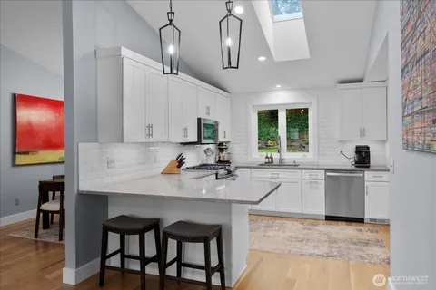 a kitchen with stainless steel appliances granite countertop a table chairs sink and cabinets
