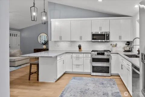 a kitchen with stainless steel appliances granite countertop a sink a stove a microwave and cabinets