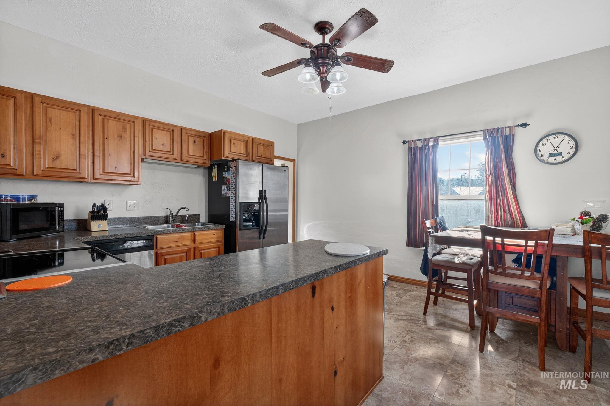 49 South 4th Street West Preston, ID 83263 - Photo 4 of 48 Kitchen featuring brown cabinetry, appliances with stainless steel finishes, dark countertops, and a ceiling fan