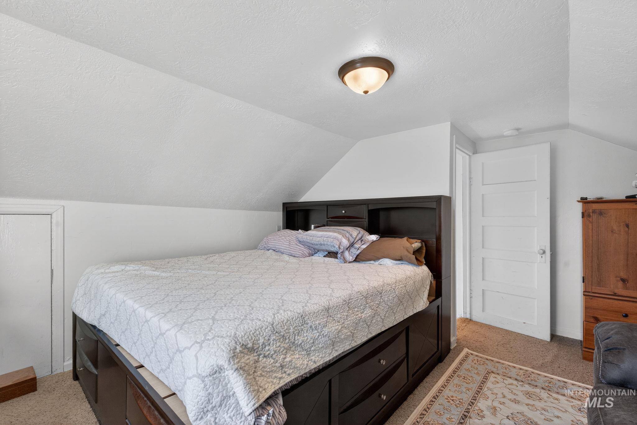 49 South 4th Street West Preston, ID 83263 - Photo 8 of 48 Bedroom featuring a textured ceiling, lofted ceiling, and light colored carpet