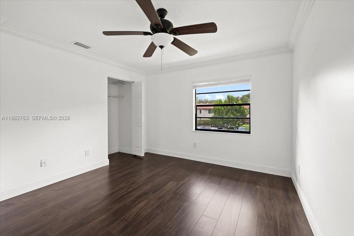 7944 Eastlake Drive, Unit D Boca Raton, FL 33433 - Photo 21 of 29 an empty room with wooden floor ceiling fan and windows
