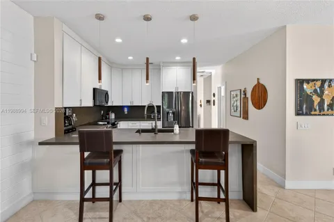 a kitchen with stainless steel appliances kitchen island granite countertop a refrigerator and a stove top oven