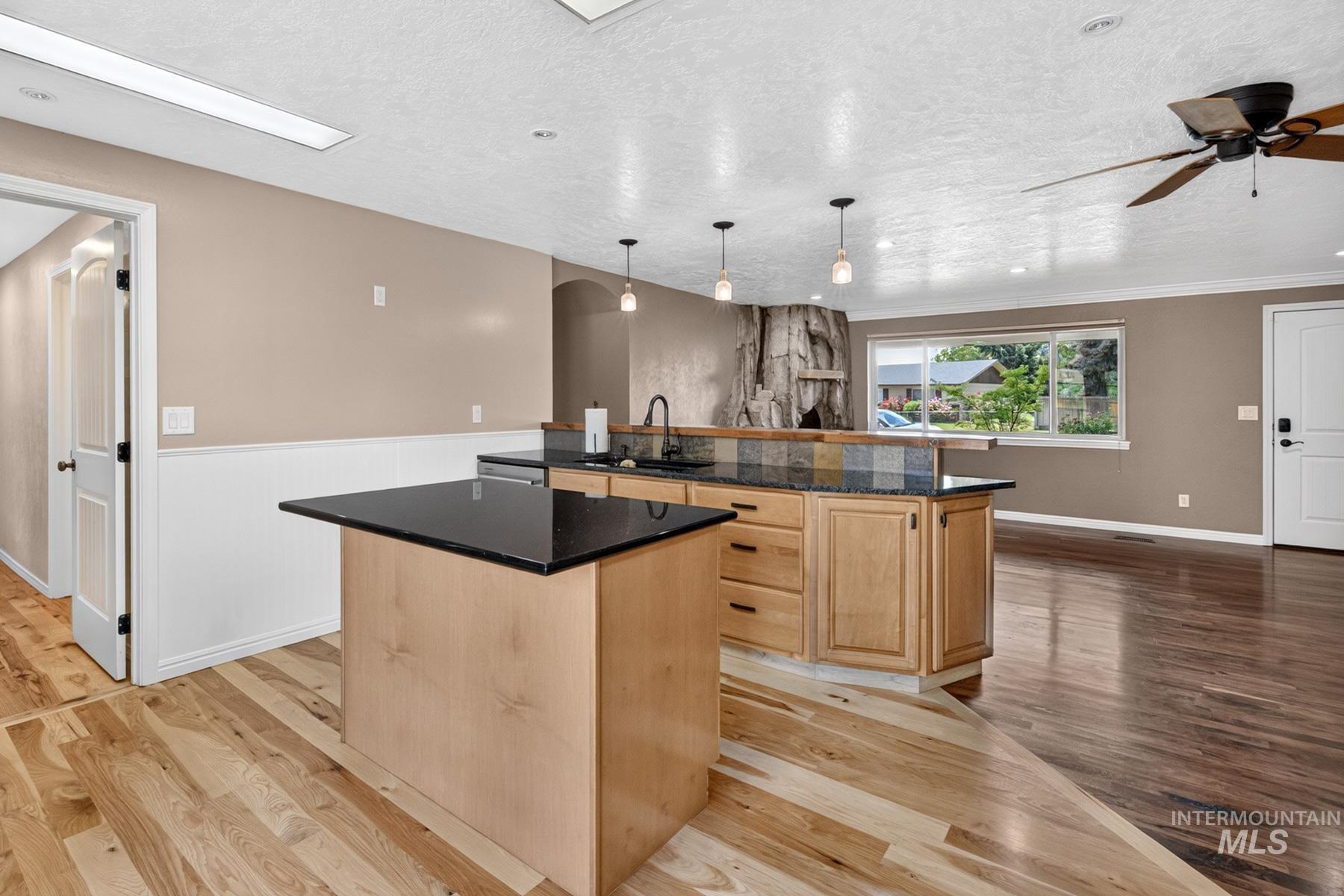 9622 Delaware Street Boise, ID 83709 - Photo 17 of 48 Kitchen island with black countertop, light wood cabinetry, and pendant lighting