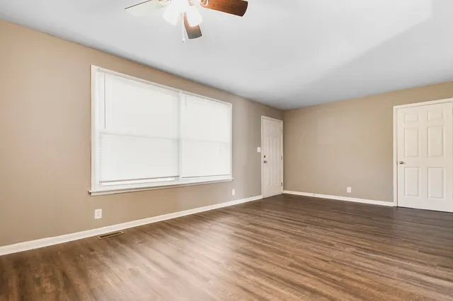 an empty room with wooden floor and windows