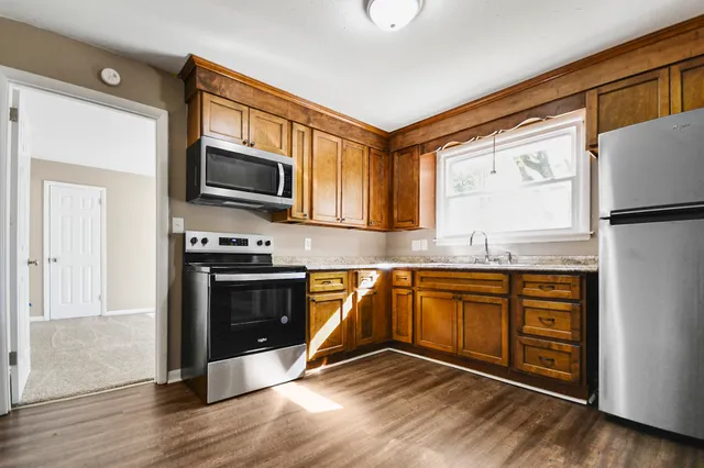 a kitchen with granite countertop a refrigerator stove top oven and sink