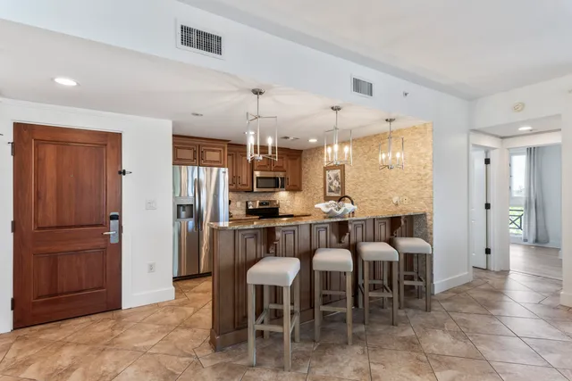 a kitchen with stainless steel appliances granite countertop a kitchen island hardwood floor a dining table and chairs