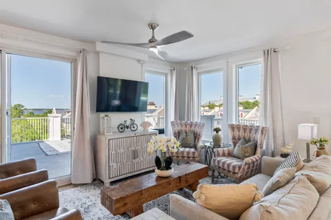 a living room with furniture a flat screen tv and a floor to ceiling window