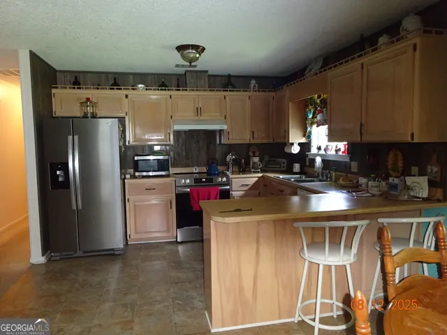 a kitchen with stainless steel appliances granite countertop a refrigerator a stove a sink and a microwave