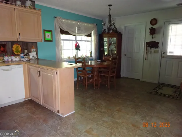 a kitchen with kitchen island granite countertop dining table chairs and a chandelier