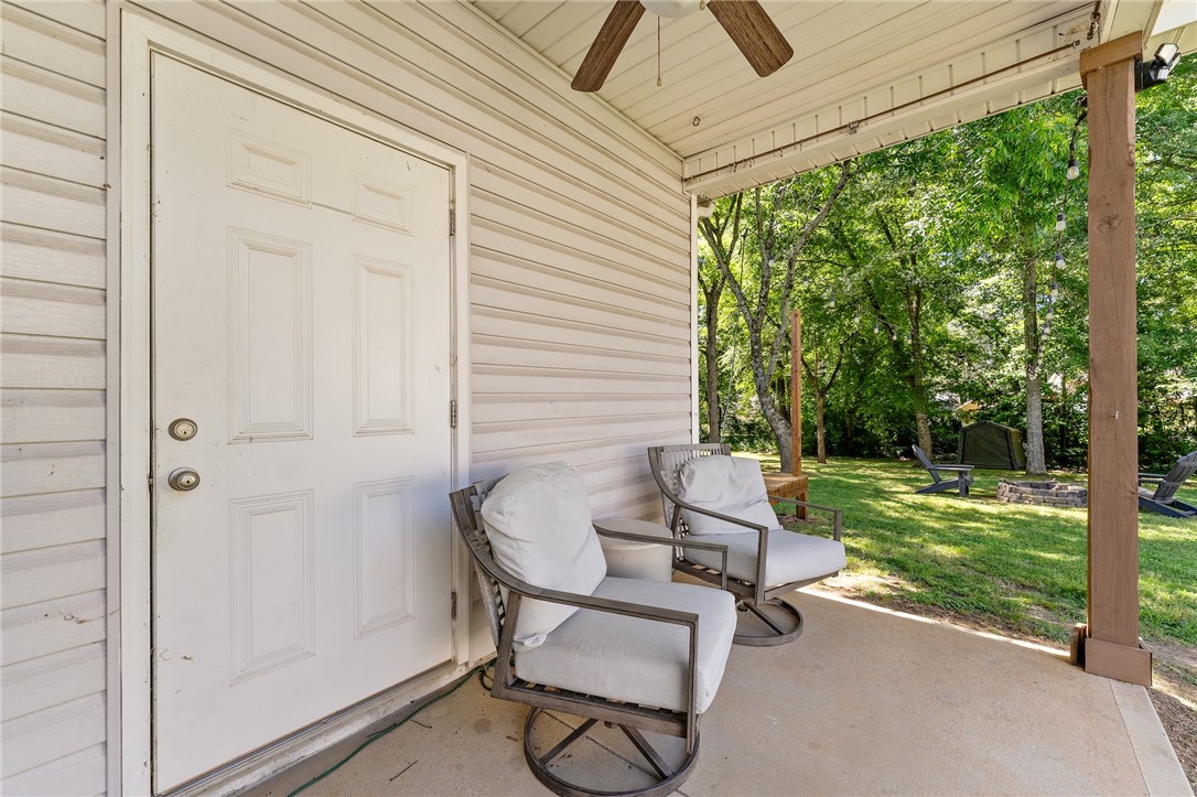 47 A Main Street Pelzer, SC 29669 - Photo 25 of 27 This cozy covered patio overlooks a private yard with lush trees, convenient storage room, and a fire pit close by for entertainment.