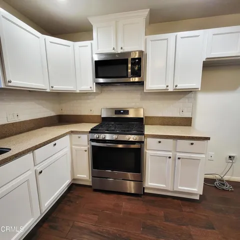 a kitchen with granite countertop white cabinets and appliances