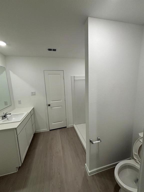 9204 Schram Road Fort Worth, TX 76179 - Photo 15 of 17 Contemporary bathroom featuring a light wood-finish floor, white vanity with an integrated sink, polished chrome faucet, and a shower stall