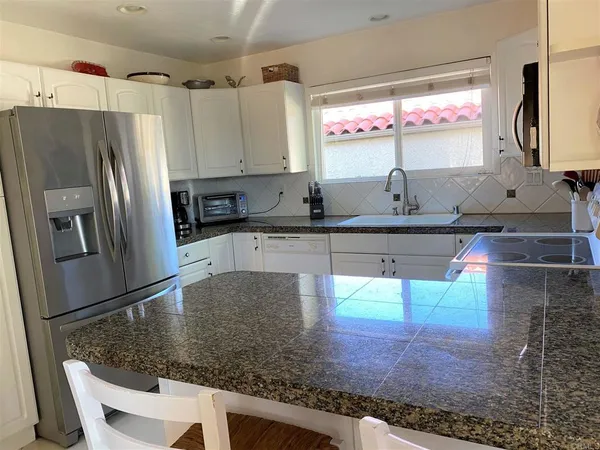 a kitchen with granite countertop a sink window and cabinets