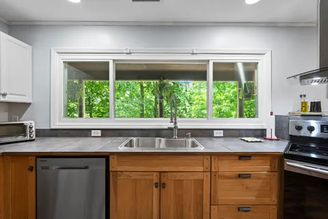 a kitchen with stainless steel appliances granite countertop a sink a refrigerator and window