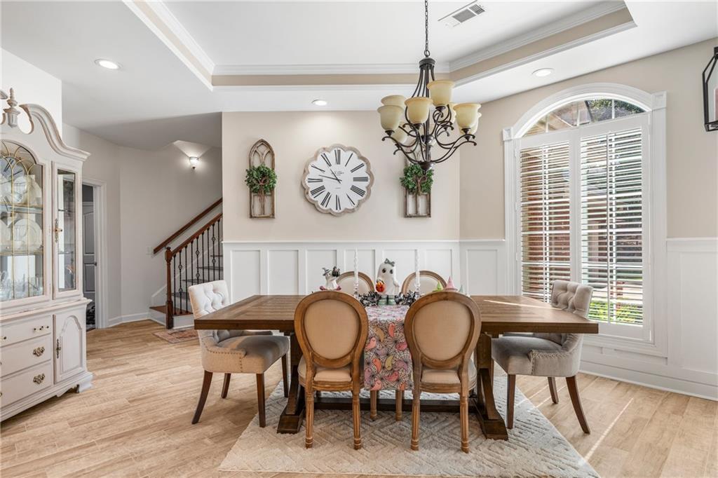 642 Nuckols Road Seale, AL 36875 - Photo 8 of 48 Tray ceiling with recessed lighting, chandelier, wainscoting, arched window with plantation shutters, and wood-finish flooring