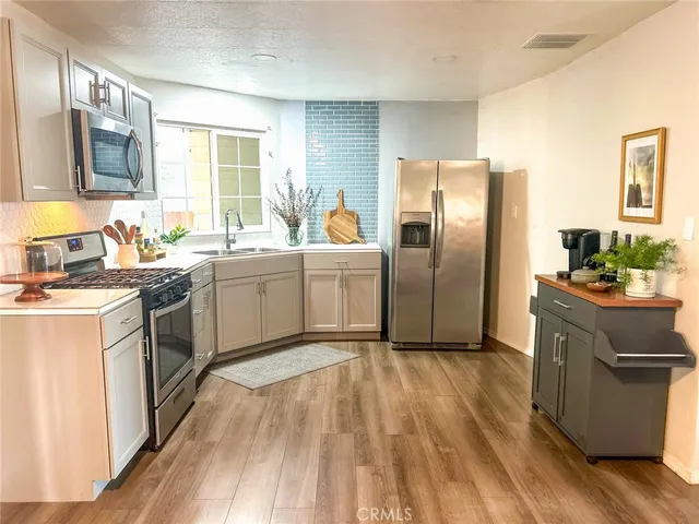a kitchen with a sink wooden floor and stainless steel appliances