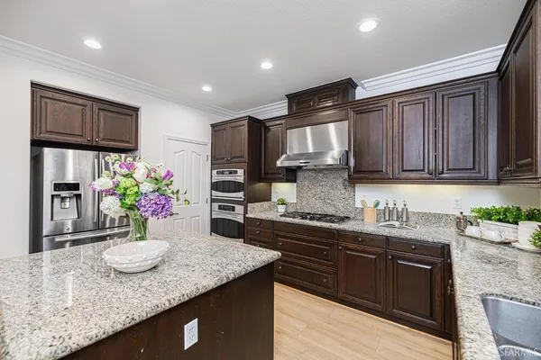 a kitchen with stainless steel appliances granite countertop a sink a stove and cabinets