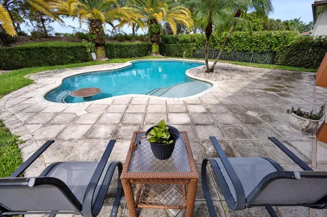 a view of a white house with swimming pool lawn chairs and a yard