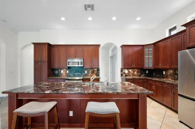 a kitchen with kitchen island granite countertop wooden cabinets and a refrigerator