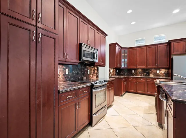 a kitchen with stainless steel appliances granite countertop wooden cabinets a stove top oven a sink and dishwasher