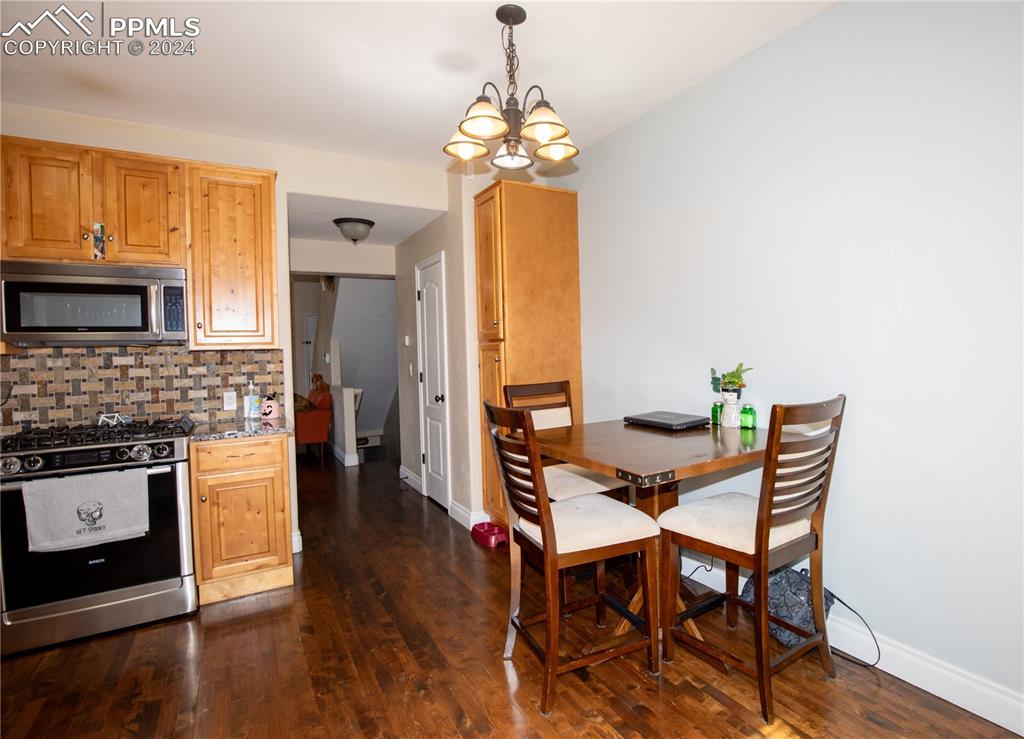 1510 York Road, Unit 103 Colorado Springs, CO 80918 - Photo 11 of 28 a dining room with wooden floor a chandelier a wooden table and chairs