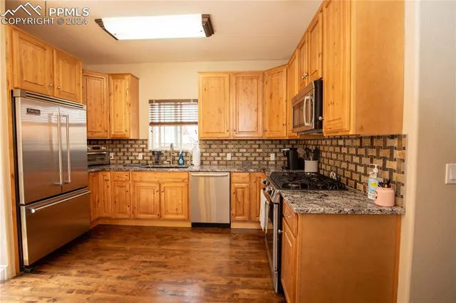 a kitchen with stainless steel appliances granite countertop a refrigerator a stove and a sink