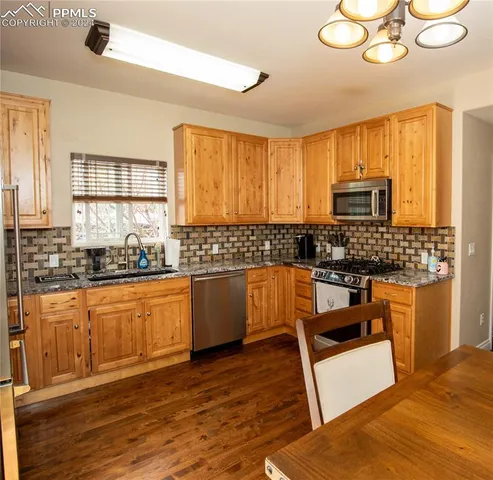 a large kitchen with granite countertop a stove a sink a window and cabinets