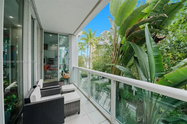a bedroom with a bed and a lamp on dresser with wooden floor