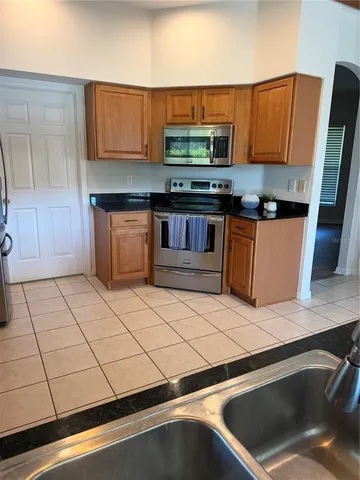 a kitchen with stainless steel appliances kitchen island granite countertop a sink a stove counter space and cabinets