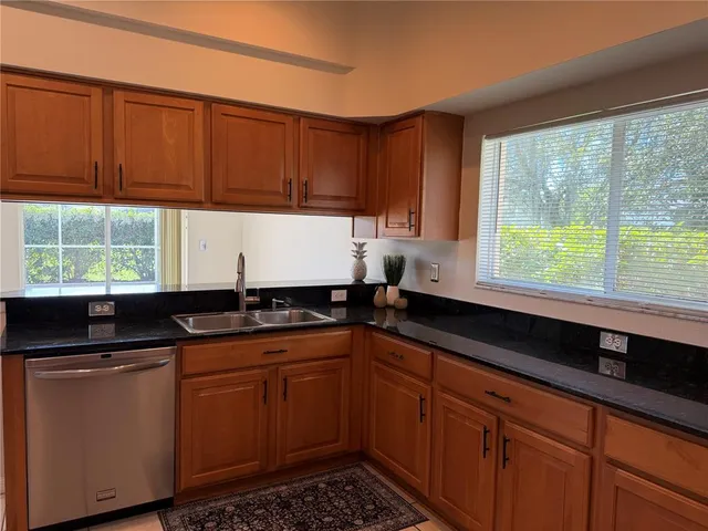 a kitchen with granite countertop wooden cabinets a sink and a window