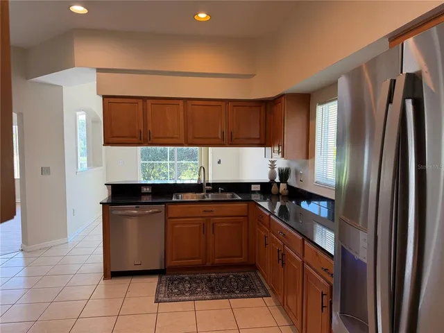 a kitchen with stainless steel appliances granite countertop a sink and a refrigerator