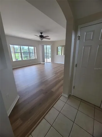 an empty room with wooden floor cabinet and windows