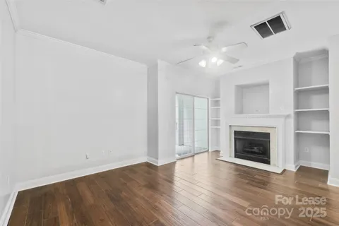 a view of an empty room with wooden floor fireplace and a window