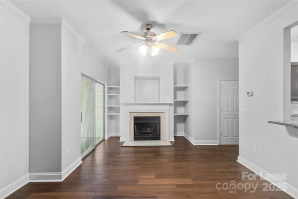 a view of an empty room with wooden floor fireplace and a window