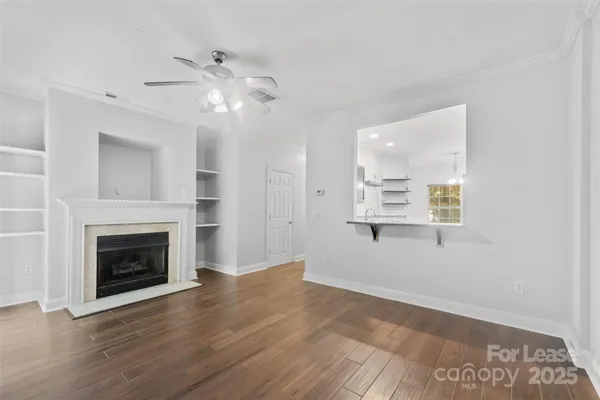 a view of an empty room with wooden floor and a fireplace