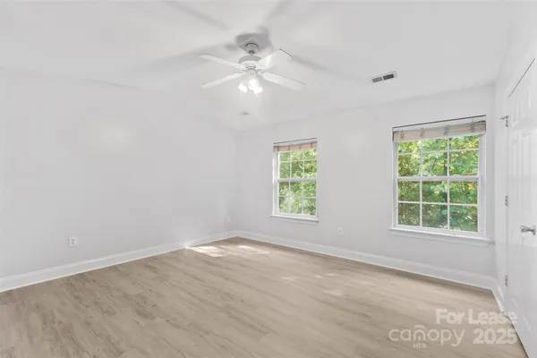 an empty room with windows and chandelier fan