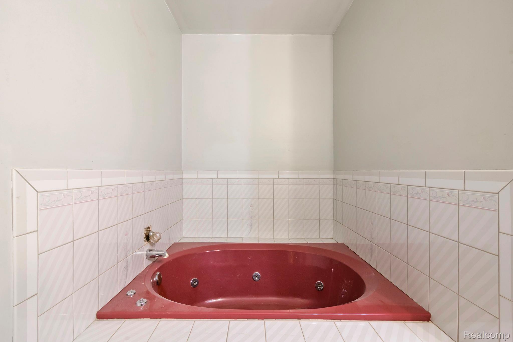 76565 McFadden Road Armada, MI 48005 - Photo 31 of 95 Corner jetted tub with tiled surround, wall-mounted faucet, and light-colored wall paint