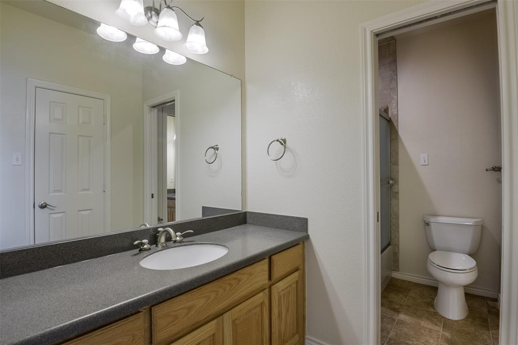 1066 W Road Waxahachie, TX 75165 - Photo 25 of 36 a bathroom with a granite countertop sink a toilet and a mirror